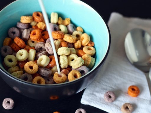 Kind dat vrolijk ontbijt aan de keukentafel met yoghurt en fruit