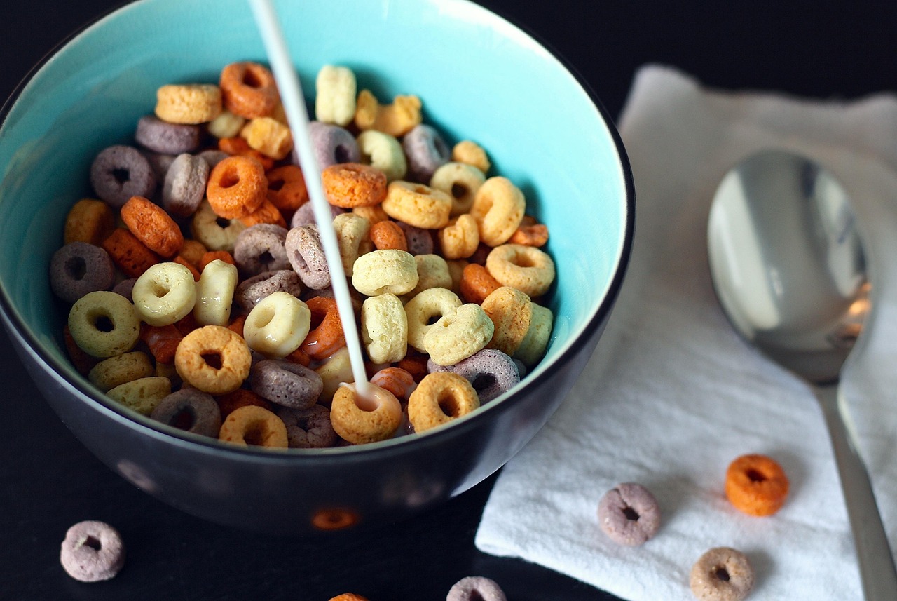 Kind dat vrolijk ontbijt aan de keukentafel met yoghurt en fruit