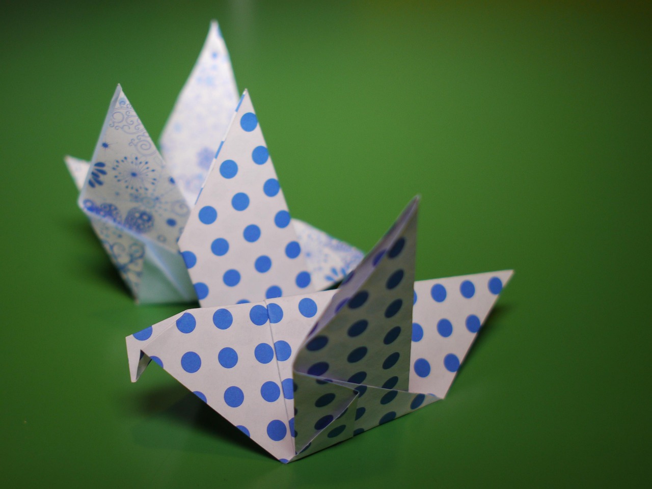Kind dat aan tafel een origamifiguur aan het vouwen is met een vel wit papier