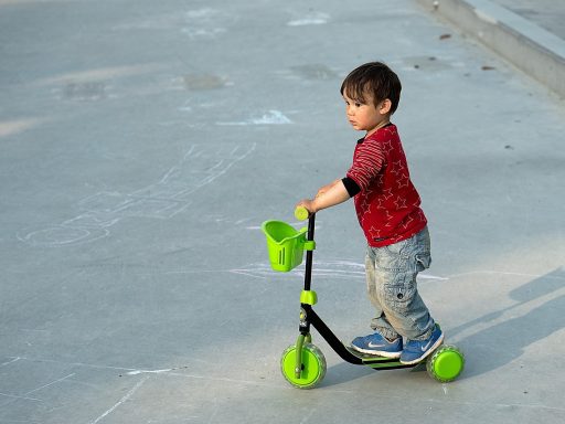 Een kind rijdt op een step op een veilige stoep terwijl het een helm draagt