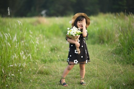 Kind speelt in hoog gras aan de rand van een bos op een zomerse dag