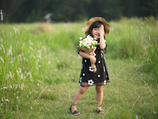 Kind speelt in hoog gras aan de rand van een bos op een zomerse dag