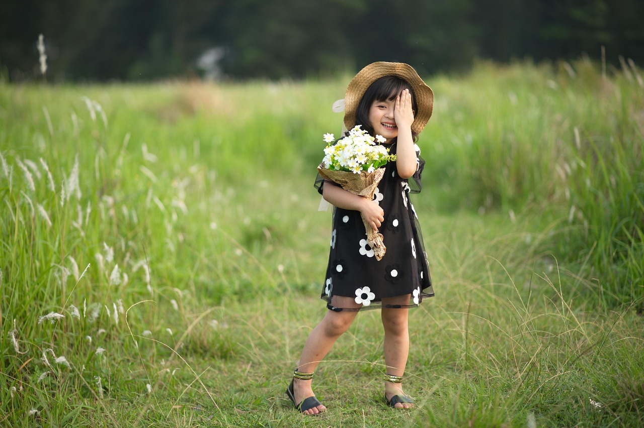 Kind speelt in hoog gras aan de rand van een bos op een zomerse dag