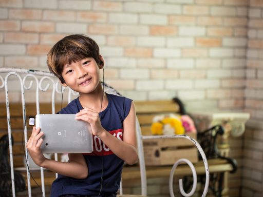 Jong kind met koptelefoon op dat naar een tablet kijkt