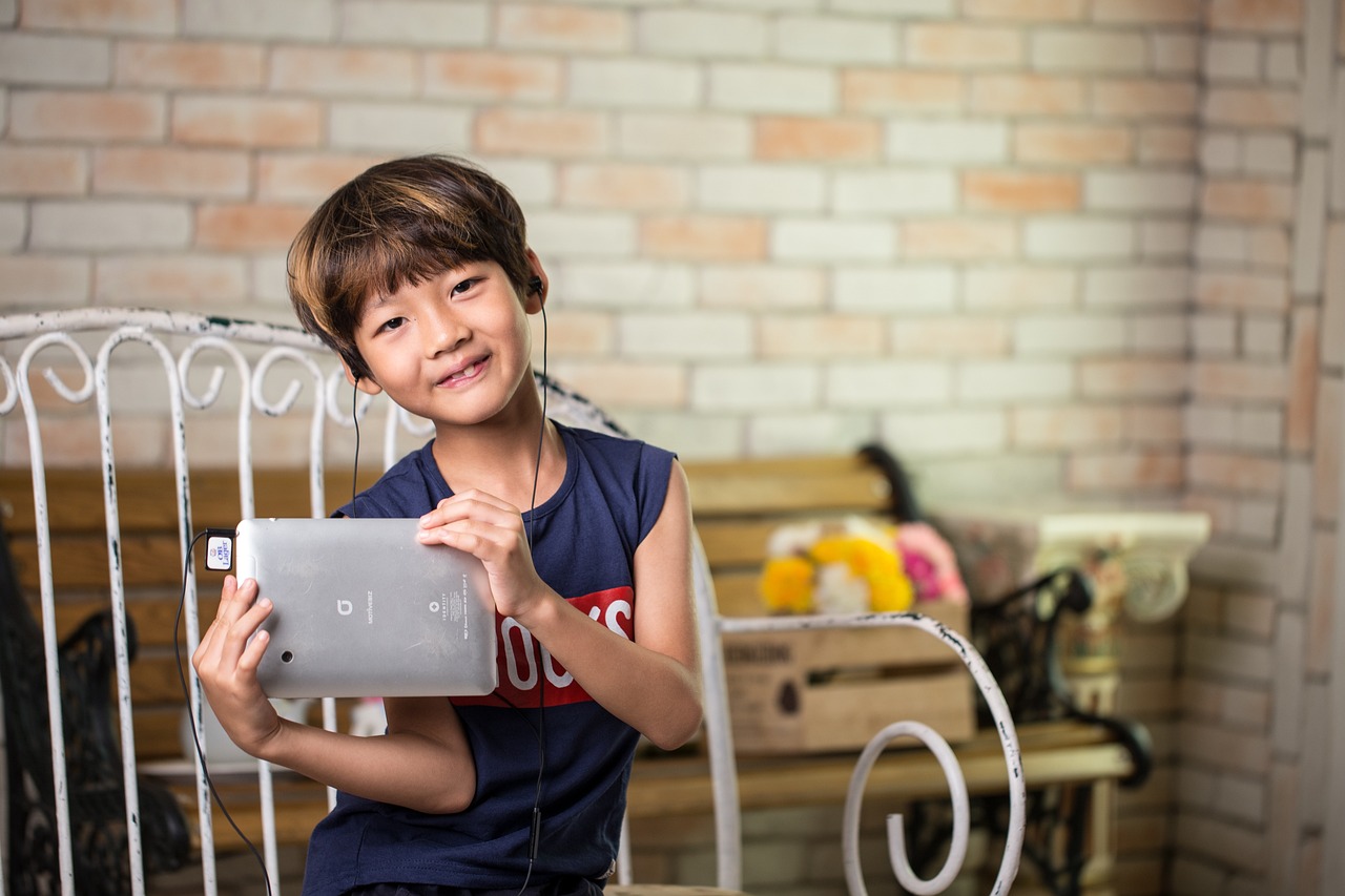 Jong kind met koptelefoon op dat naar een tablet kijkt