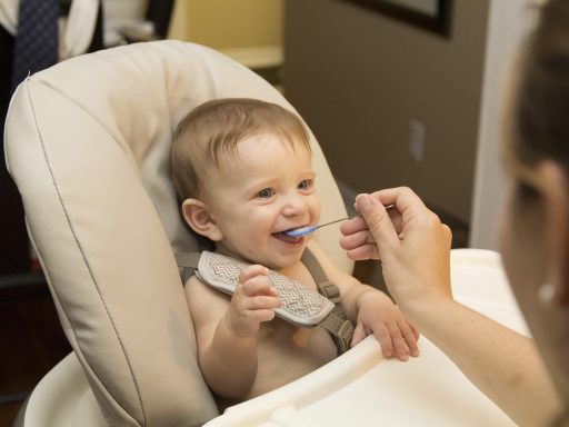 Baby in kinderstoeltje krijgt een eerste hapje van een lepeltje