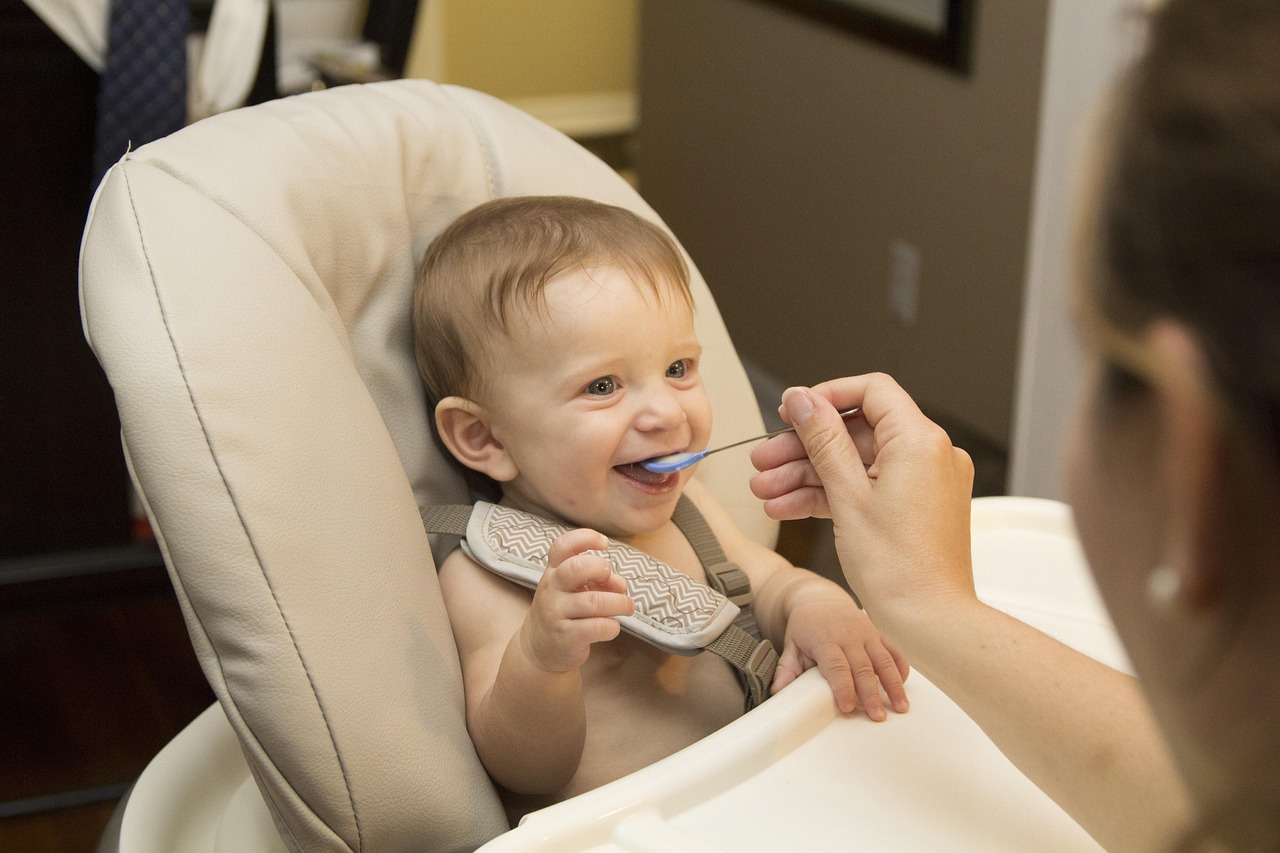 Baby in kinderstoeltje krijgt een eerste hapje van een lepeltje