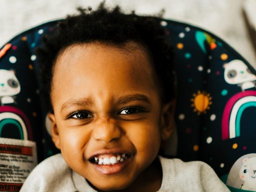Kleine peuter zit huilend op de vloer tijdens een woedeaanval terwijl een ouder naast hem neerhurkt