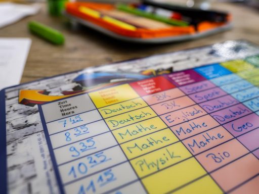 Een kind dat twijfelend voor zijn huiswerk zit en de pen vasthoudt zonder te schrijven