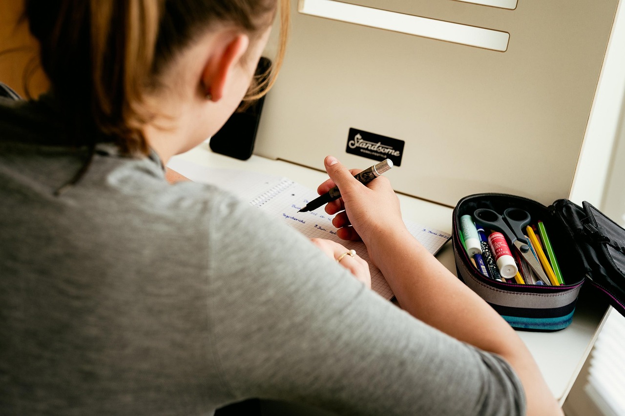 Kind doet huiswerk aan een bureau zonder scherm in de buurt